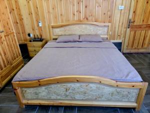 drewnianym łóżkiem w pokoju z drewnianymi ścianami w obiekcie atoom lodge w mieście Dżarasz