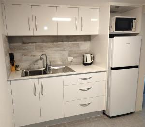cocina con armarios blancos, fregadero y nevera en Cozy Bedroom with Ensuite - Amazing City Location en Townsville