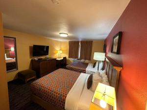 a hotel room with a bed and a flat screen tv at Royal Victorian Motel in Port Angeles