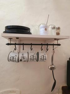 une étagère avec des tasses et des ustensiles sur un mur dans l'établissement Los tarcos Guest House TILCARA LOFT, à Tilcara