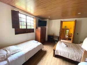 a bedroom with two beds and a window and a mirror at Hotel Villa Mercedes Colonial in Sopó