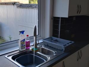 a kitchen sink with a dish drying rack next to a window at Arise Comfort Home - Dumers Lane, Radcliffe, Bury, Manchester in Radcliffe