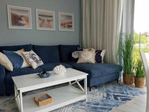 a living room with a blue couch and a white table at WYSPA MEW - apartament PREMIUM z prywatnym ogrodem, 150 m od plaży in Gąski
