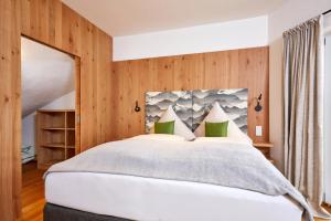 a bedroom with a large white bed with wooden walls at Das Gsteig in Garmisch-Partenkirchen