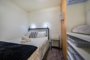 a small bedroom with a bed with white sheets and pillows at Snow Ski Apartments 23 in Falls Creek