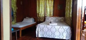 Habitación pequeña con cama y mesa en Nellie's Tourist Inn- Port Barton en San Vicente