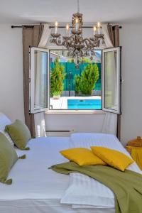 a bedroom with a white bed and a window at Nudist friendly villa with fence arround pool and garden to relax and enjoy in Podstrana