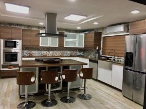 a kitchen with a island with bar chairs in it at Villa Barranca Este Moderna & Lujosa Casa De Campo Golf Resort in La Romana