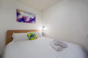 um quarto com uma cama branca e toalhas em Snow Ski Apartments 24 em Falls Creek