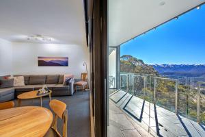 a living room with a couch and a balcony with a view at Snow Ski Apartments 24 in Falls Creek