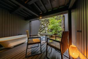 a balcony with a tub and two chairs and a table at Tsuki-Akari Takayama - Japanese Traditional House with Open-air Bath in Takayama