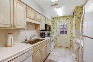 cocina con armarios blancos, fregadero y nevera en Fairway Oaks Villa Condo, en Amelia Island