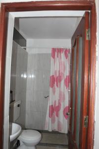 a bathroom with a toilet and a shower curtain at SAM House in Mindelo
