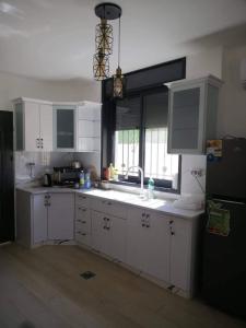 傑里科的住宿－Al bader villa，厨房配有白色橱柜、水槽和窗户。