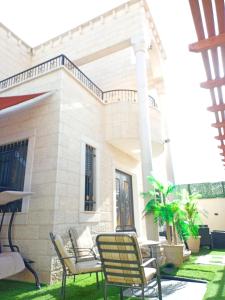 Al bader villa في أريحا: فناء مع كراسي ومنزل