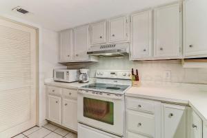 a kitchen with white cabinets and a stove top oven at Pool View Beachwood Condo in Fernandina Beach