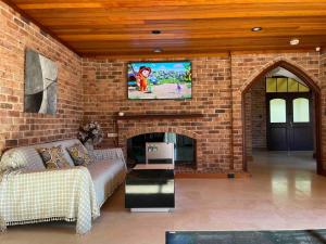 a living room with a couch and a tv on a brick wall at 悉尼Killara Luxurious 8BR House 360 degree view in Saint Ives