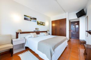 1 dormitorio con 1 cama blanca grande y TV en Hotel Residencial Salema, en Salema