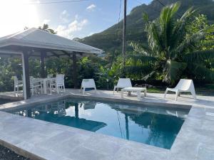 einen Pool mit Stühlen und einem Pavillon in der Unterkunft Villa Ura in Uturoa