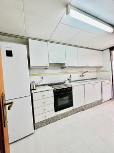 cocina con armarios blancos y nevera blanca en Apartamento con Piscina 3 habitaciones, en Sueca