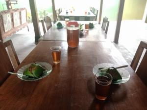 een houten tafel met twee glazen bier en een bord eten bij Pendopo Kayuwanan Homestay Syariah in Yogyakarta