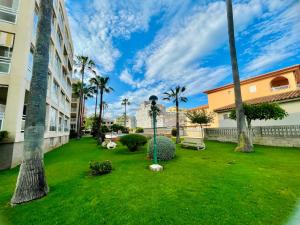 un patio verde con palmeras y un edificio en Apartamento con Piscina 3 habitaciones, en Sueca