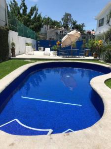 a blue swimming pool with an umbrella in a yard at Departamento Rouge in Cuernavaca