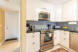 cocina con armarios blancos y horno de acero inoxidable en Charming townhome w/ private backyard & fire pit, en Palm Beach Gardens