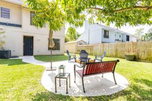 棕櫚灘花園的住宿－Charming townhome w/ private backyard & fire pit，一个带长凳、桌子和一棵树的院子