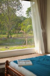 een slaapkamer met een raam met uitzicht op een rivier bij Lukmailhontaiton (ลูกไม้หล่นใต้ต้น) 