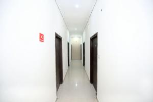 a corridor of a building with white walls and doors at Flagship 13088 Hotel Basant in Rāja Sānsi