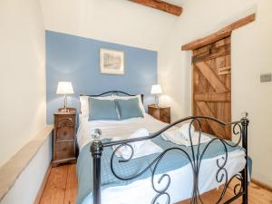 sypialnia z łóżkiem z niebieską ścianą w obiekcie Ellen Cottage w mieście Burford