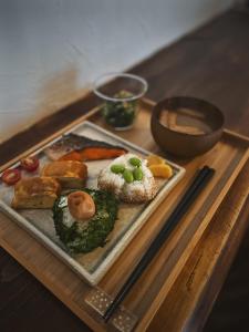 ein Teller mit Essen auf einem Holztisch mit Essstäbchen in der Unterkunft 島ぐらしカフェchigoohagoo 男性のみ宿泊不可 Couples & Single Females Only in Oshima