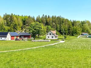 a green field with a house and a road at Holiday home FÄRGELANDA VI in Färgelanda