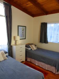 a bedroom with two beds and a dresser and window at Theo's Cottage in Waikanae
