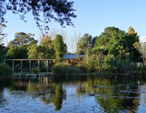 a pond with a pavilion and a duck in the water at Theo's Cottage in Waikanae