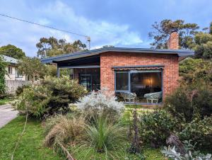 a brick house with a large window in a garden at Cosy Brick Beachouse - ALL INCLUDED in Inverloch