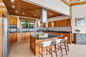 una cocina con armarios de madera y una isla con taburetes. en Villa Dos Playas, en Playa Hermosa