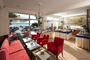 a restaurant with red chairs and tables and a view of the ocean at Hotel Stanger in Lovran