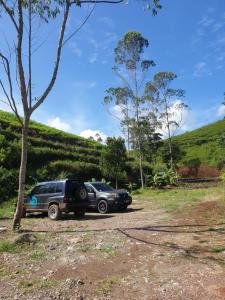 two cars parked on a dirt road next to a hill at Kancah Nangkub in Pengalengan