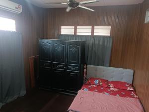 um quarto com uma cama e um armário preto em RS HOMESTAY DUNGUN em Kampong Pak Sabah