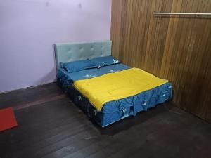 uma cama num quarto com uma colcha amarela em RS HOMESTAY DUNGUN em Kampong Pak Sabah