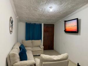 a living room with two couches and a flat screen tv at La Posada Manabita in Portoviejo