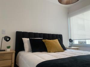 1 dormitorio con cama blanca y negra con almohadas amarillas en Departamento en Recoleta en Buenos Aires