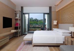 Shenzhen Marriott Hotel Golden Bay في شنجن: غرفة نوم بسرير ابيض ونافذة كبيرة