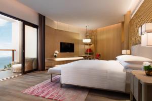 a bedroom with a large white bed and a desk at Shenzhen Marriott Hotel Golden Bay in Shenzhen