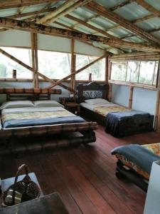 two beds in a room with wooden floors and windows at Cabaña el Ensueño (GUADUA, BAMBU) in Pereira