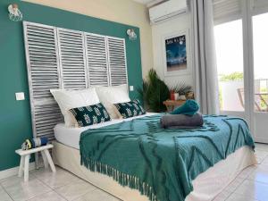 1 dormitorio con 1 cama con pared verde en La Perle Iléenne, vue imprenable sur la mer., en Les Trois-Îlets
