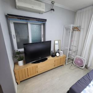 una sala de estar con TV en un centro de entretenimiento de madera en JUN house - Foreign Only en Busan