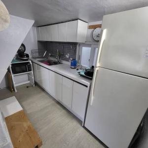 uma cozinha com armários brancos e um frigorífico branco em JUN house - Foreign Only em Busan